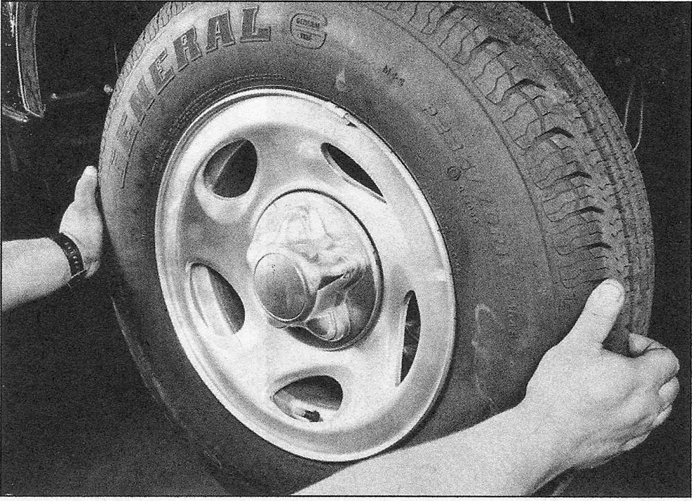 With the steering wheel locked and the vehicle raised, grasp the front tire as shown and try to move it back-and-forth - if any play is noted, check the tie-rod ends for looseness